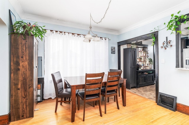 dining space with ornamental molding, visible vents, and light wood-type flooring