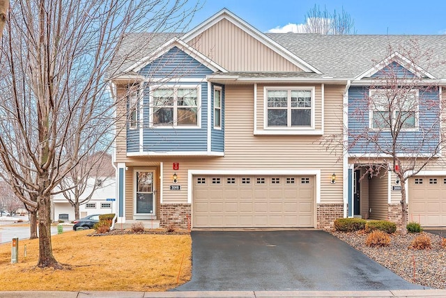 view of front of house with aphalt driveway, a garage, brick siding, and board and batten siding