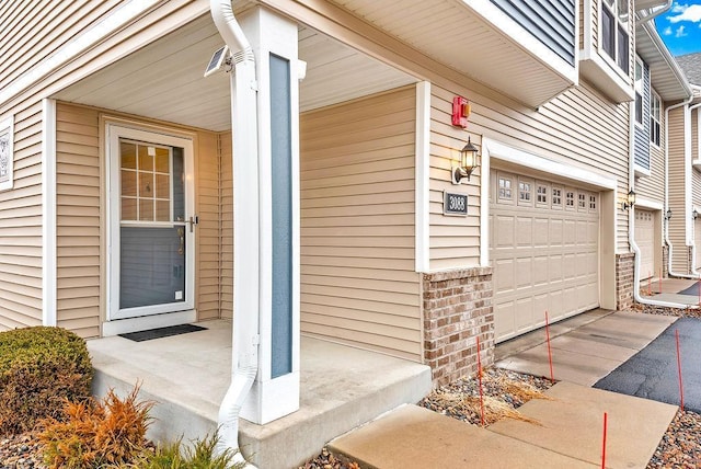 doorway to property featuring brick siding, concrete driveway, and a garage