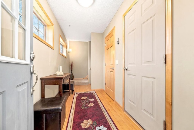 hall featuring light wood-style floors and a textured ceiling