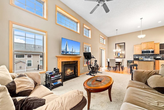 living room featuring a ceiling fan, a textured ceiling, a healthy amount of sunlight, and a fireplace