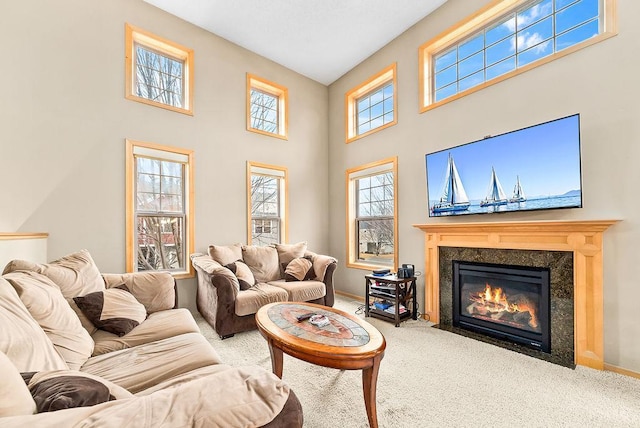 living room with carpet flooring, a fireplace, a high ceiling, and baseboards