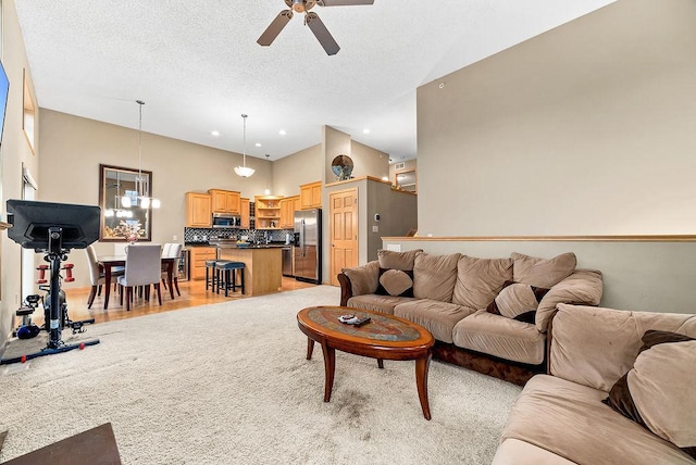 living area featuring light wood-style flooring, a textured ceiling, a ceiling fan, and a towering ceiling