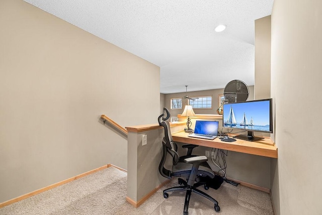 carpeted office space featuring baseboards and a textured ceiling