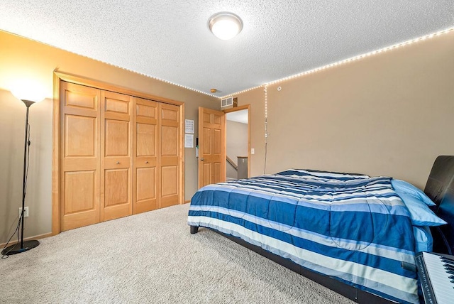 bedroom with a closet, visible vents, a textured ceiling, and carpet floors