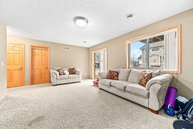 carpeted living area featuring visible vents, baseboards, and a textured ceiling