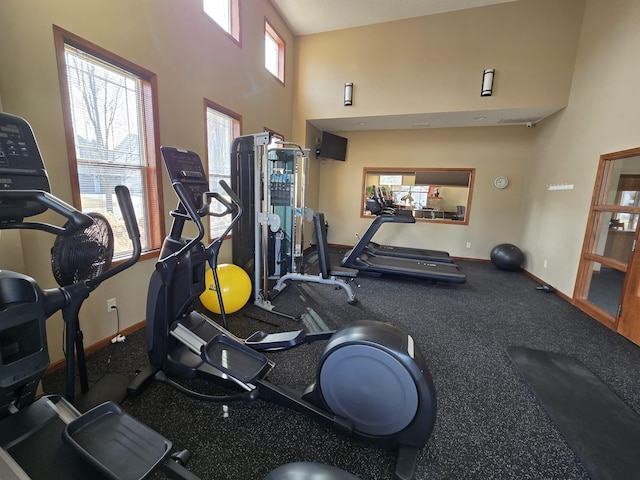 workout area featuring baseboards and a high ceiling