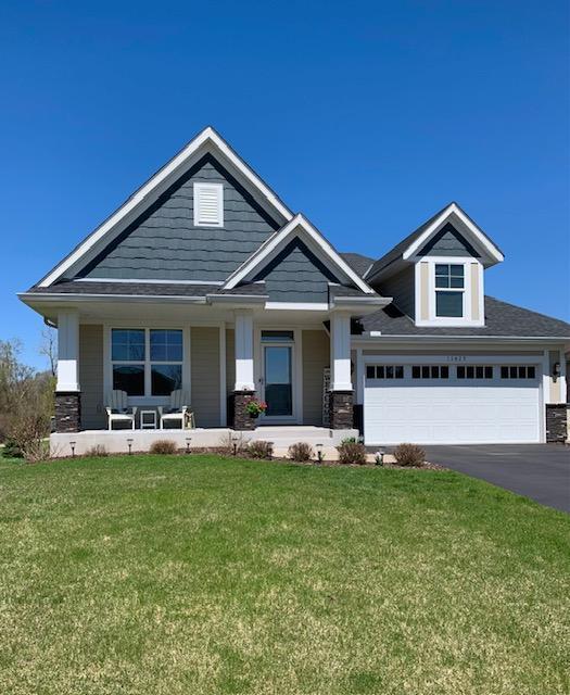 craftsman house with covered porch, driveway, stone siding, and a front lawn
