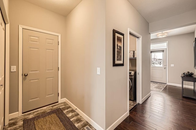 entrance foyer with washer / dryer, baseboards, and dark wood-type flooring