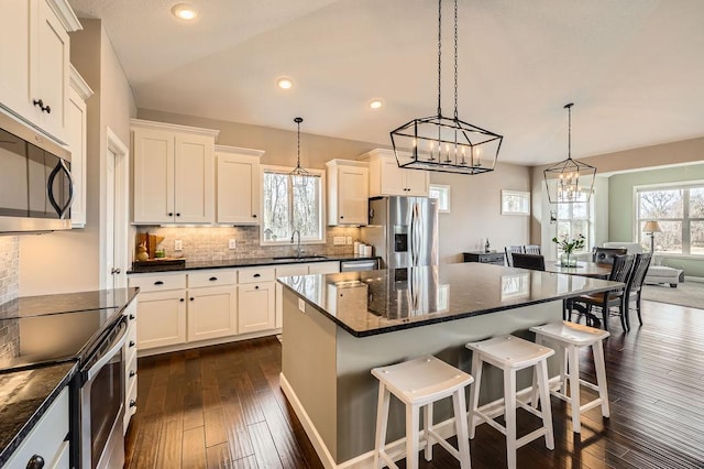 kitchen featuring a kitchen breakfast bar, a center island, tasteful backsplash, a sink, and stainless steel appliances