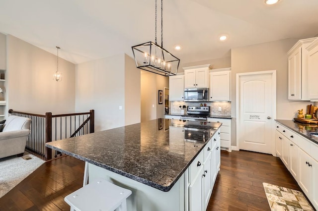 kitchen with an inviting chandelier, white cabinetry, appliances with stainless steel finishes, and dark wood-style floors