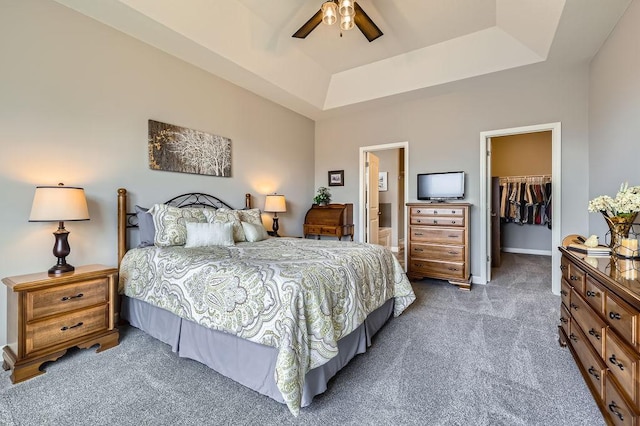 carpeted bedroom featuring ceiling fan, a raised ceiling, ensuite bath, a spacious closet, and a closet