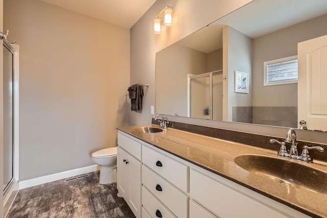 full bathroom featuring toilet, baseboards, a shower stall, and a sink