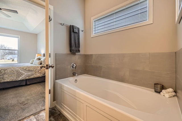 ensuite bathroom featuring plenty of natural light, a bath, ceiling fan, and ensuite bath