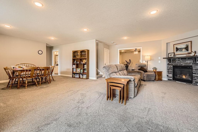 living room featuring baseboards, carpet flooring, a textured ceiling, and a fireplace