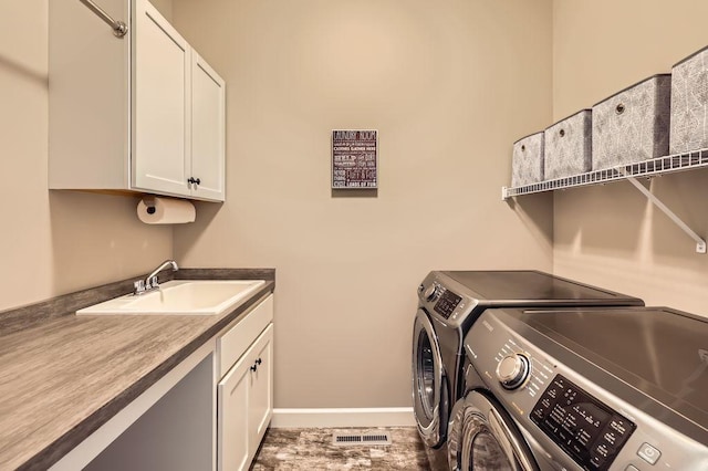laundry area featuring visible vents, cabinet space, a sink, baseboards, and washer and clothes dryer