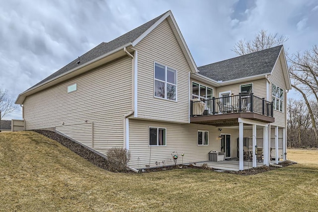 back of house featuring a lawn, a patio, roof with shingles, and a deck