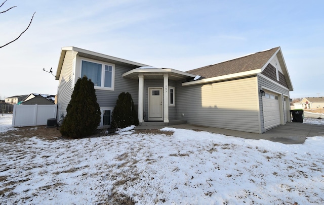 view of front of home with a garage, central AC, driveway, and fence