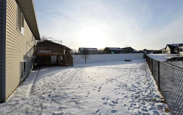 yard layered in snow featuring a residential view, a fenced backyard, and stairs