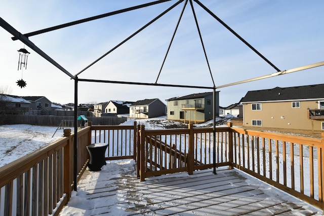 snow covered deck with glass enclosure, a residential view, and a fenced backyard