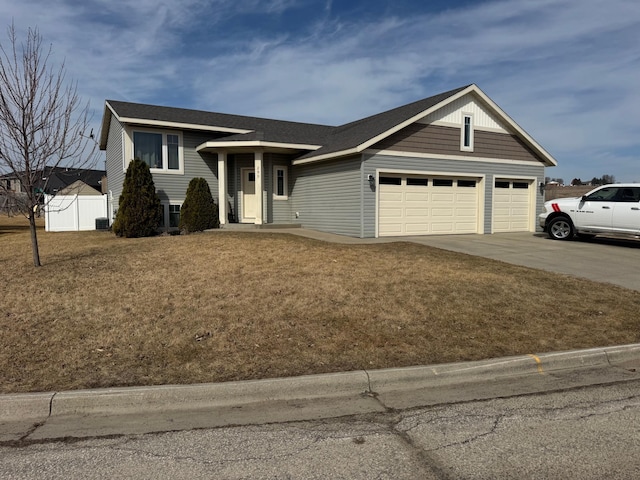 view of front of home with a front lawn, fence, concrete driveway, central AC unit, and an attached garage