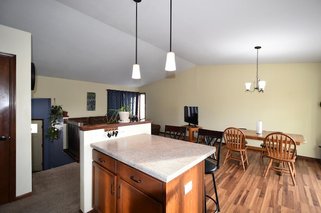kitchen featuring a kitchen island, decorative light fixtures, lofted ceiling, a kitchen breakfast bar, and wood finished floors