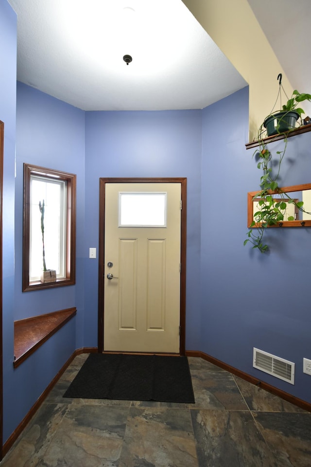 entrance foyer with visible vents, baseboards, and stone finish floor