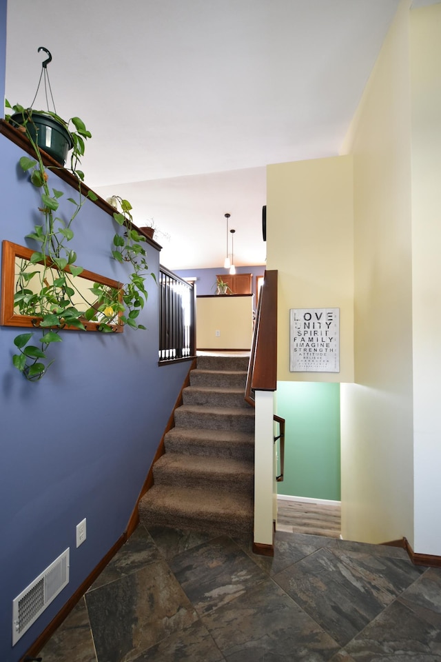stairway featuring visible vents, stone finish flooring, and baseboards