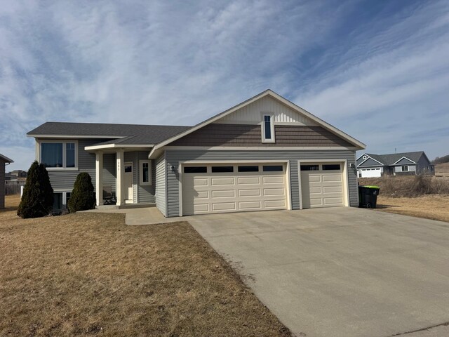 view of front of property featuring an attached garage, concrete driveway, and a front yard