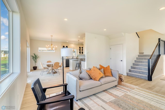 living room with stairs, a notable chandelier, recessed lighting, and light wood-type flooring