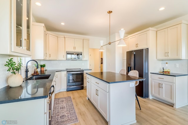 kitchen featuring a sink, dark countertops, light wood-type flooring, and stainless steel appliances