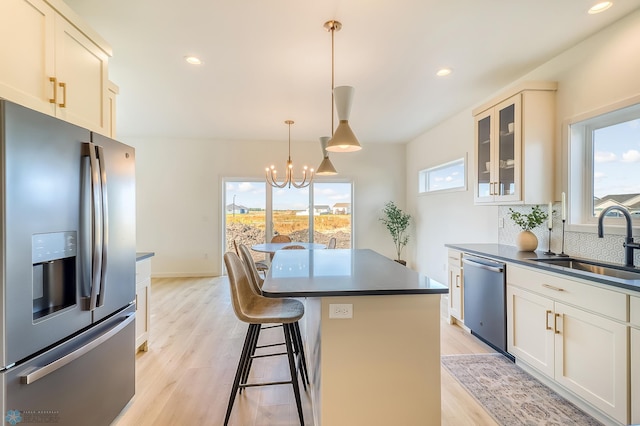 kitchen with an inviting chandelier, a sink, decorative backsplash, appliances with stainless steel finishes, and dark countertops