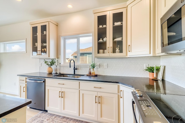 kitchen with decorative backsplash, dark countertops, appliances with stainless steel finishes, and a sink