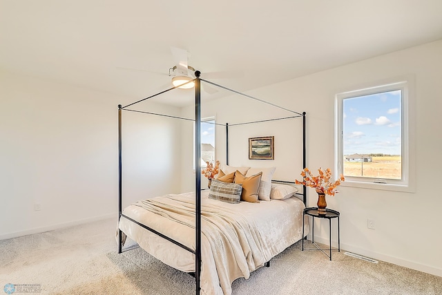 bedroom featuring ceiling fan, visible vents, baseboards, and light carpet