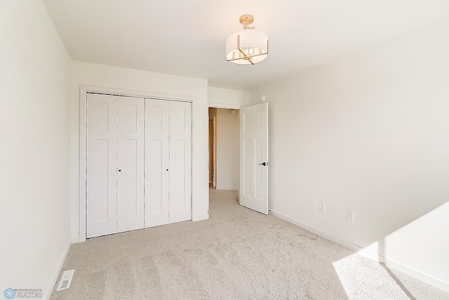 unfurnished bedroom featuring a closet, light colored carpet, and baseboards