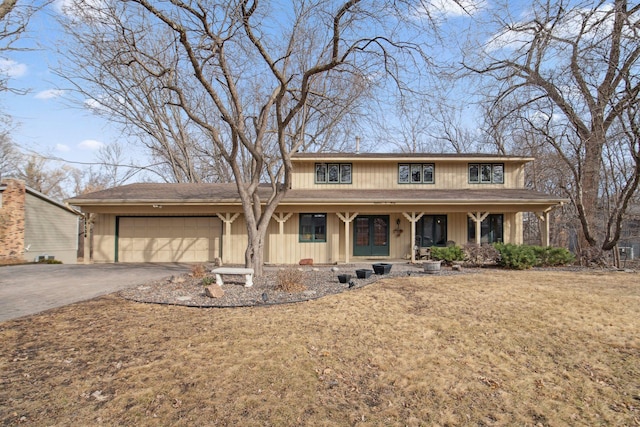 view of front of house featuring a porch, a front yard, driveway, and a garage