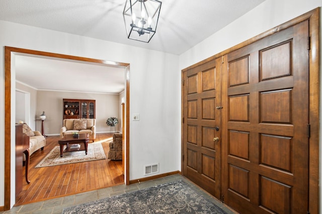 entrance foyer with visible vents, baseboards, a chandelier, and stone finish floor