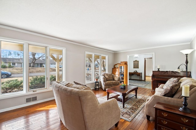 living area featuring visible vents, ornamental molding, baseboards, and hardwood / wood-style floors