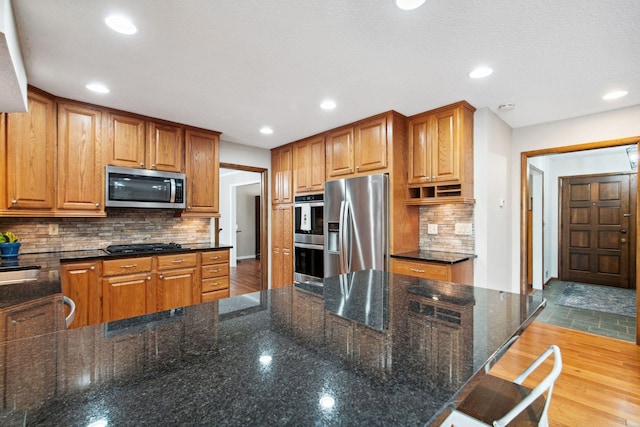 kitchen featuring recessed lighting, stainless steel appliances, wood finished floors, and decorative backsplash