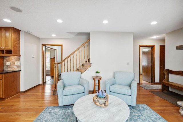 living area with recessed lighting, light wood-style floors, and stairs