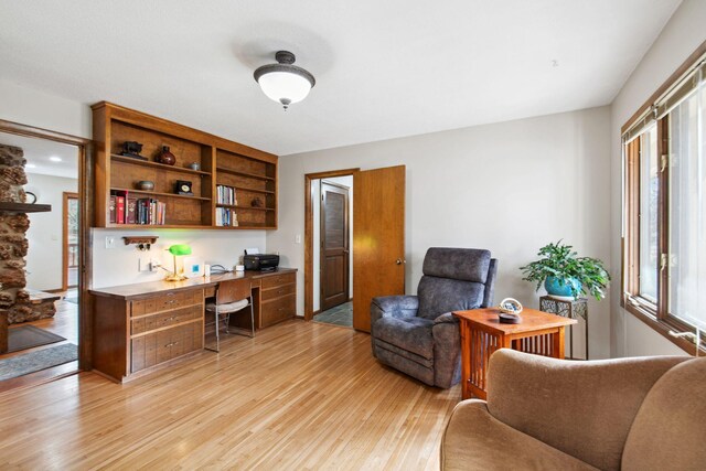 office area with light wood-style floors and built in study area