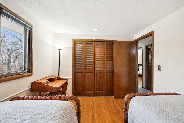 bedroom featuring light wood-type flooring, a closet, and a textured ceiling