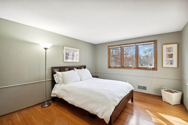 bedroom with visible vents, baseboards, and wood finished floors