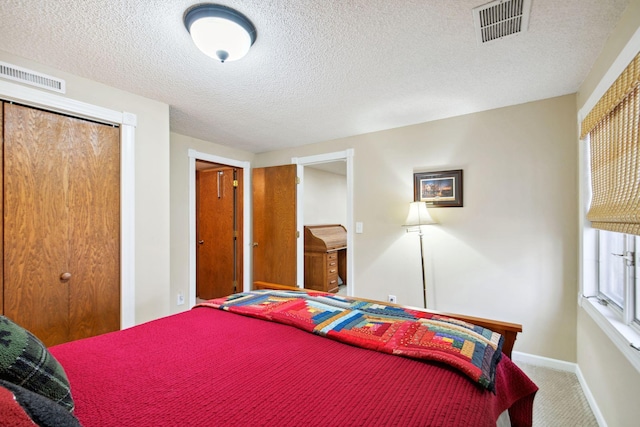 carpeted bedroom featuring visible vents, baseboards, a textured ceiling, and a closet