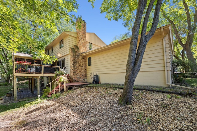 view of side of home featuring a wooden deck, a chimney, and stairway