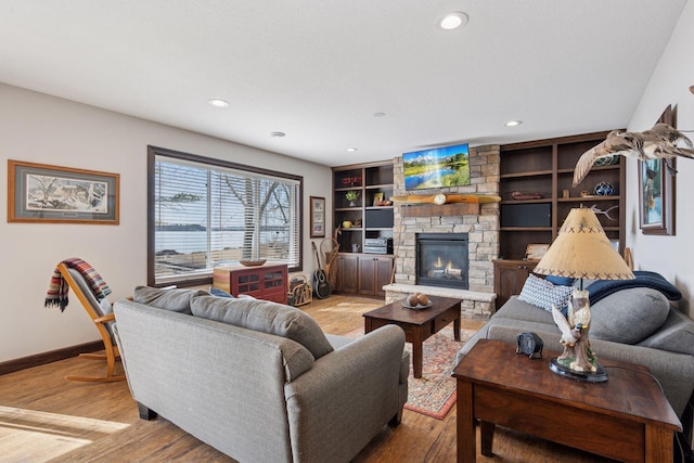 living area with a stone fireplace, recessed lighting, light wood-style floors, and baseboards