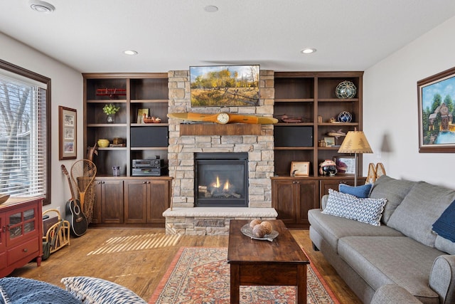 living area featuring recessed lighting, light wood-type flooring, and a fireplace