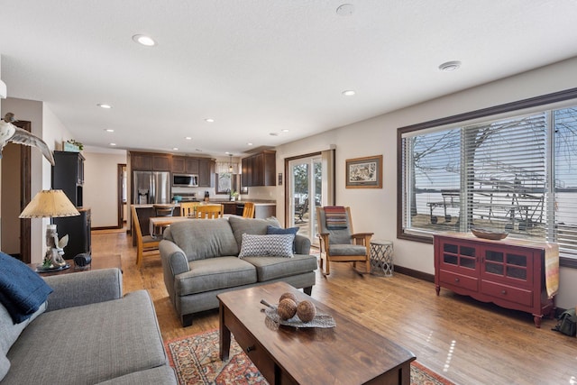 living room featuring recessed lighting, baseboards, and light wood-style floors