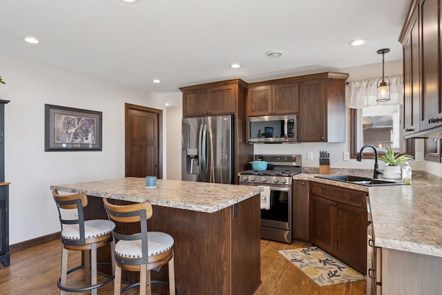 kitchen with appliances with stainless steel finishes, a center island, light countertops, and a sink