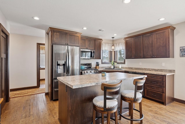 kitchen featuring light countertops, a center island, light wood finished floors, and stainless steel appliances